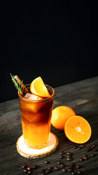 A glass of iced americano black coffee and layer of orange