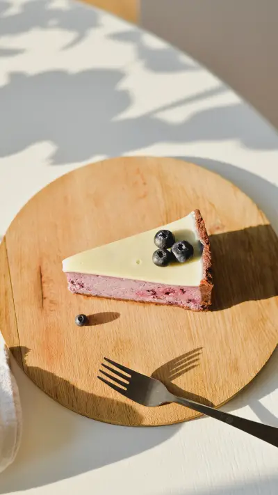 Slice of cheesecake with berries on a wooden plate
