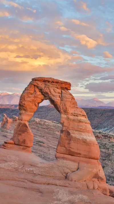 Utah delicate arch near sunset mountains in the background