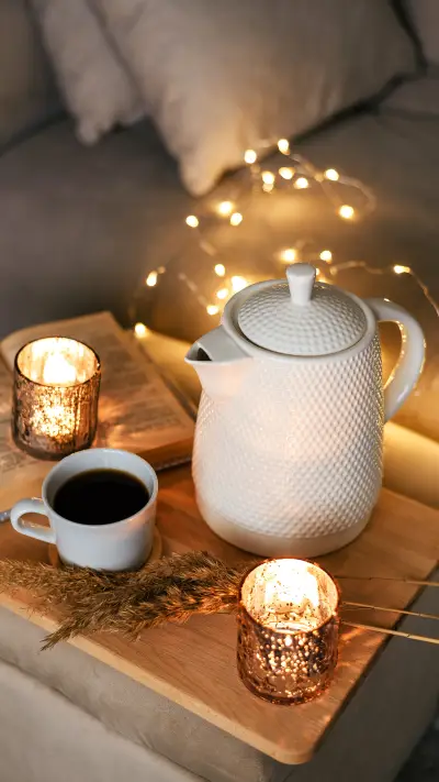 Teapot, book, cup of coffee and candles on a wooden table