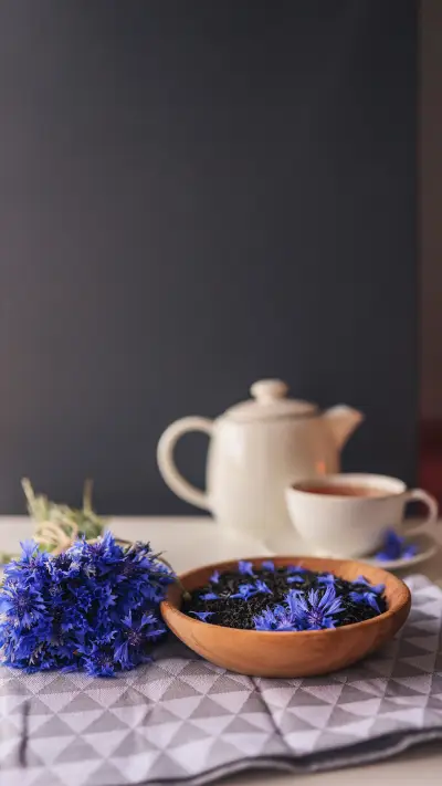 Black natural tea with cornflower petals on the table