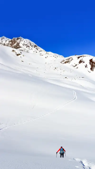 Man hiking on snowshoes and mountain snow panorama