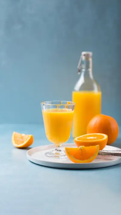 Fresh orange juice in glass with bottle and orange pieces