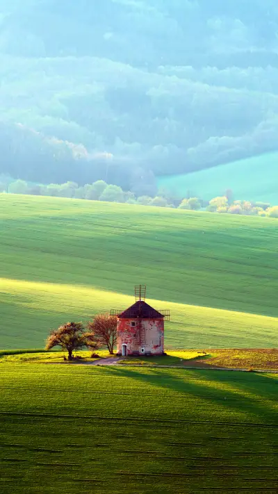 An old windmill and green sunny spring hills