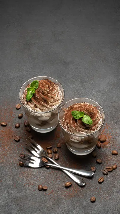 Two portions Classic tiramisu dessert in a glass on dark